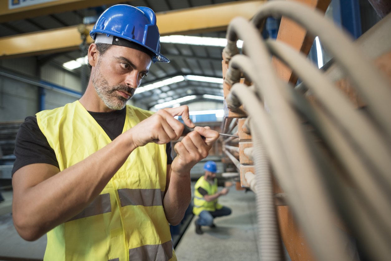 Industrial worker adjusts the screws that hold the wiring of the cement factory